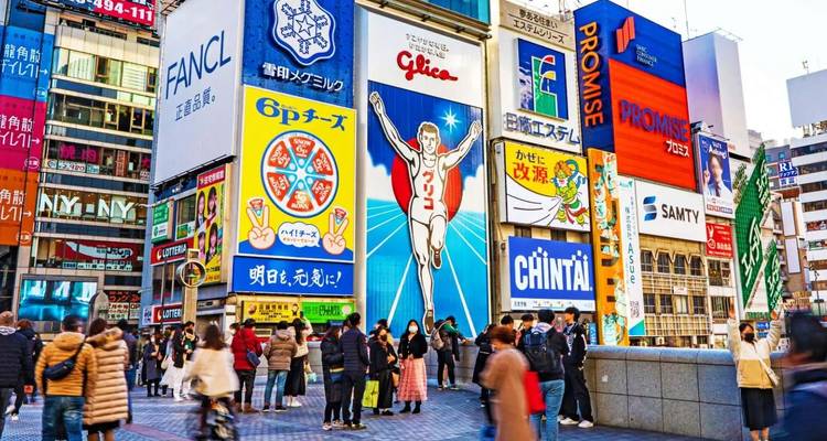 De bruisende Dotonbori-straat met het beroemde Glico rennende man reclamebord en kleurrijke neonreclames trekt avondmenigten aan.