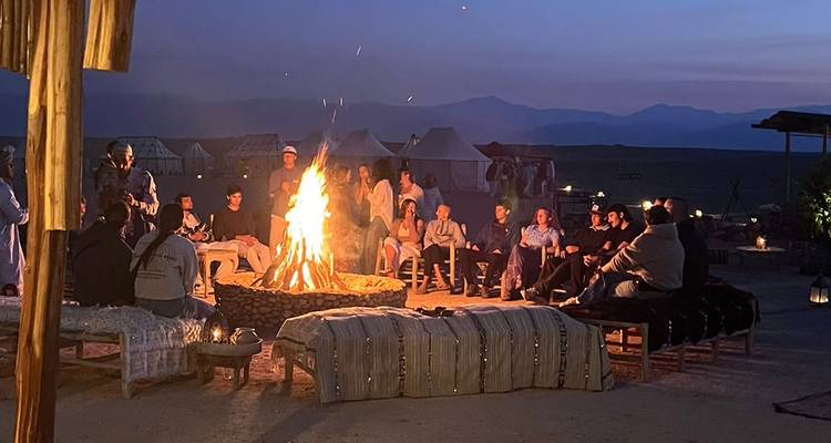 Reisende versammelten sich bei Abenddämmerung um ein großes Lagerfeuer in einem Wüstenlager.