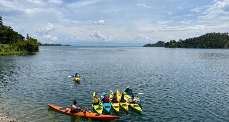 Des kayaks colorés avec leurs pagayeurs se rassemblent sur les eaux bleues calmes d'un grand lac sous un vaste ciel.