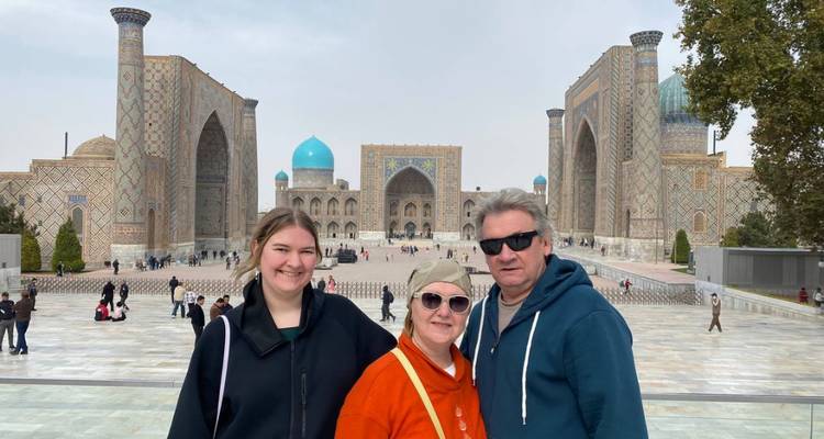 Drie reizigers poseren voor de turquoise koepels en majestueuze bogen van het Registan-plein.
