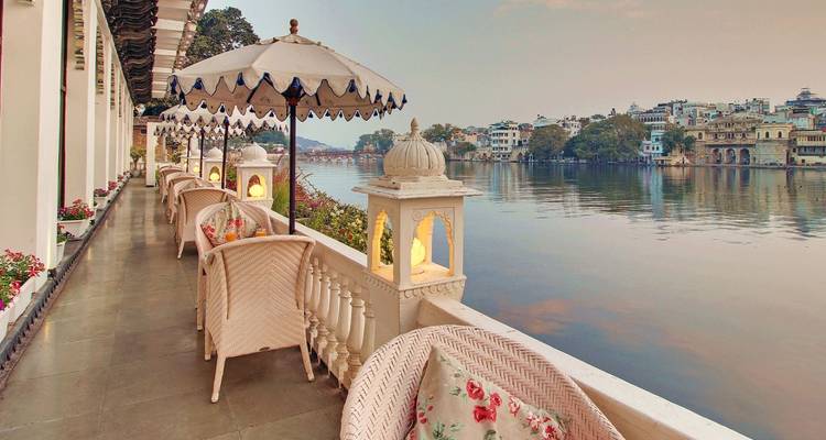 Charmante véranda au bord de l'eau avec parasols et lanternes donnant sur le lac Pichola à l'aube.