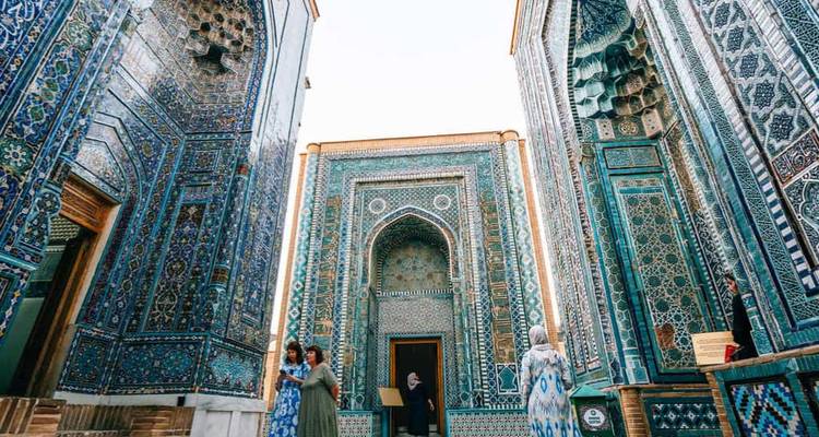 Bezoekers wandelen tussen de torenhoge met blauwe tegels bedekte mausolea van Samarkands Shah-i-Zinda necropolis.