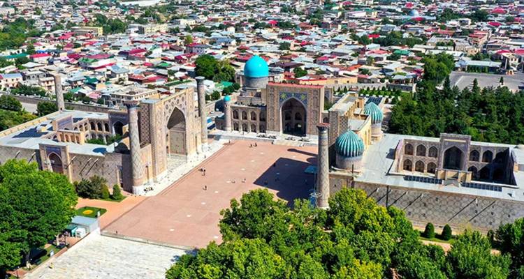 Luchtfoto vanuit hoge hoek van Samarkand's Registan met zijn drie grootse madrassa's en de stedelijke uitbreiding daarachter.