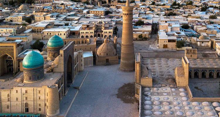 Dronebeeld van het oude centrum van Boechara met turkooizen koepels, de Kalyan-minaret en honingkleurige gebouwen.