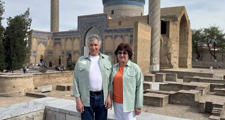 Een stel staat voor het blauwkoepelige Gur-e Amir mausoleum, versierd met ingewikkeld tegelwerk en hoge minaretten.