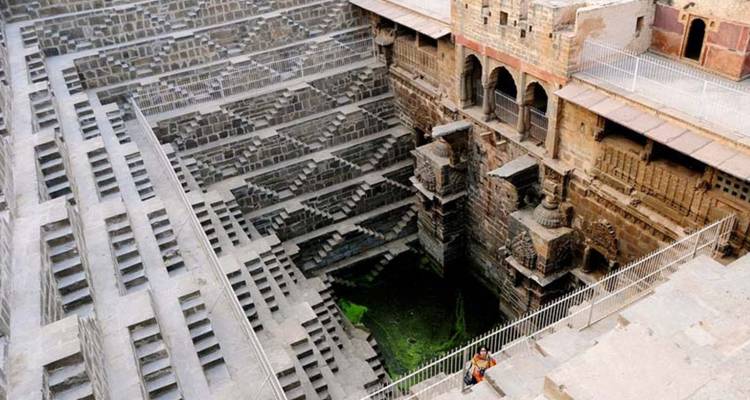 Un visiteur solitaire contemple les marches géométriques vertigineuses du puits à degrés Chand Baori.