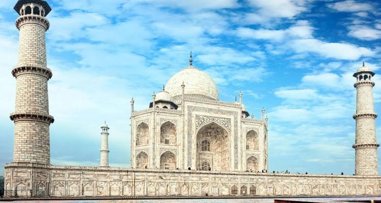 Iconique Taj Mahal en marbre blanc encadré par un ciel bleu et flanqué de minarets jumeaux.
