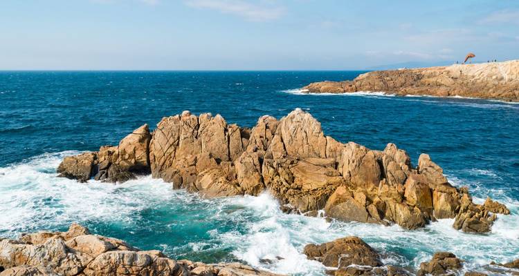 Afloramiento rocoso en la costa atlántica con olas rompiendo contra formaciones de granito dorado