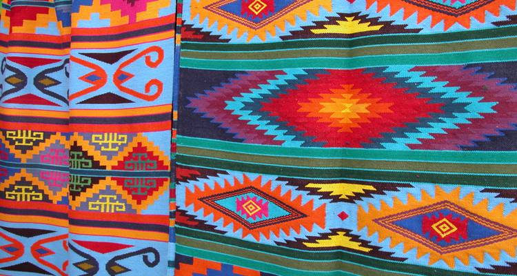 Nebeneinander ausgestellte, leuchtend bunte gewebte Textilmuster.