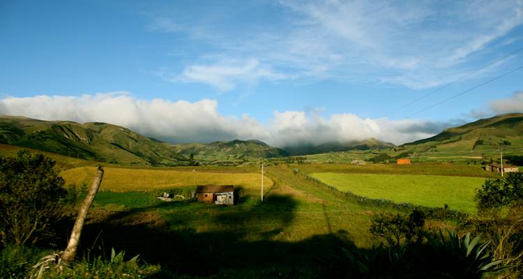 Friedliche Andenlandschaft mit Flickenteppichfeldern, sanften Hügeln und dramatischer Wolkenbank.