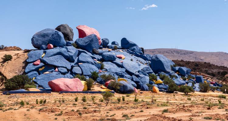 Cluster van massieve granieten rotsblokken geschilderd in levendig blauw, roze en geel in Tafraoute's woestijn.