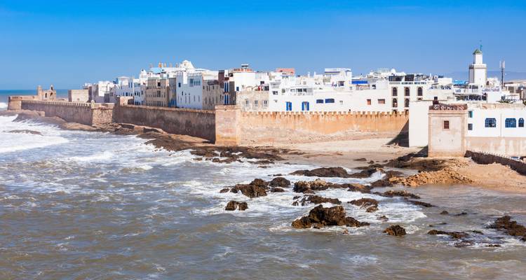 Nahansicht von weiß getünchten Essaouira-Gebäuden auf sandigen Festungsanlagen neben rauer See