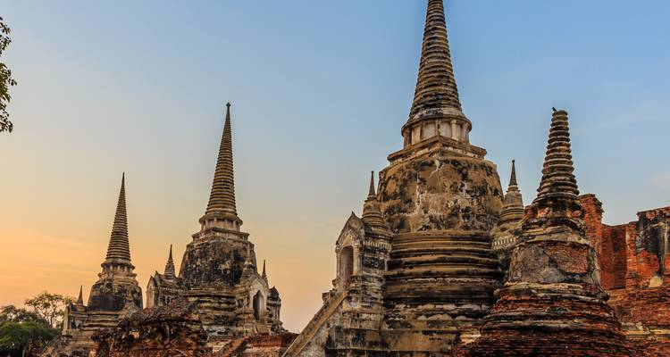 Rij van Ayutthaya stupa's afgetekend tegen warme avondlucht creërend een dramatische historische scène