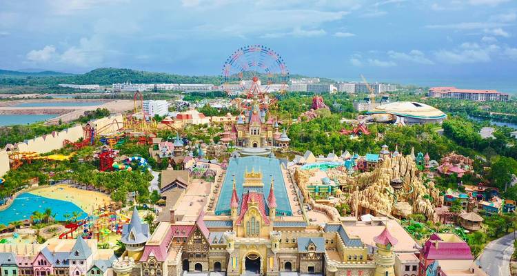 Vue aérienne éclatante du parc à thème VinWonders avec des châteaux colorés, des manèges et une grande roue au loin, entourés de verdure tropicale sur l'île de Phu Quoc