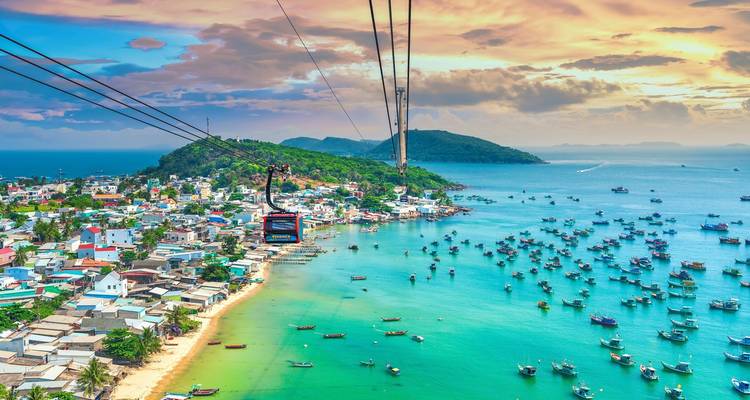 Vue aérienne du téléphérique Hon Thom glissant au-dessus des baies turquoise remplies de bateaux de pêche au large de Phu Quoc.
