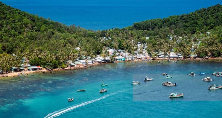 Baie cristalline bordée de collines luxuriantes et d'un petit village côtier sur l'île de Phu Quoc.