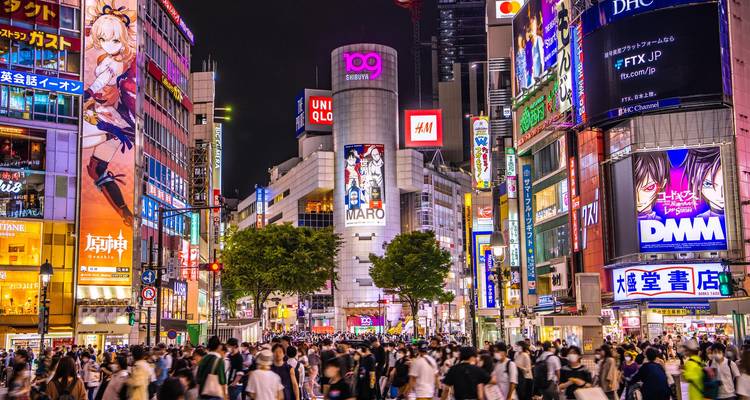 Scène nocturne vibrante au carrefour de Shibuya avec enseignes au néon et foules denses.