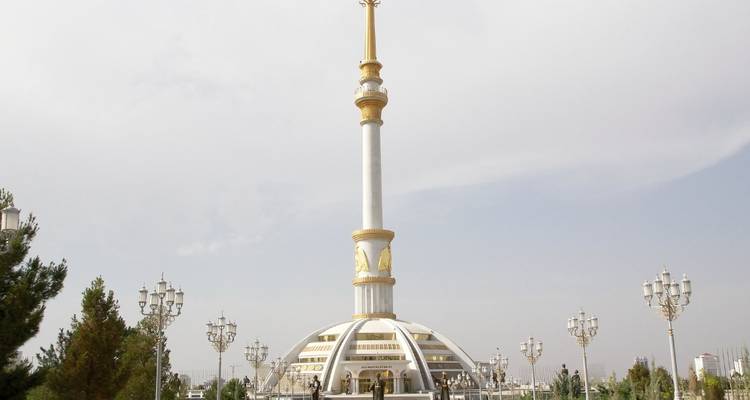 Hohes weiß-goldenes Unabhängigkeitsdenkmal, das sich über angelegte Gärten in Aschgabat erhebt.