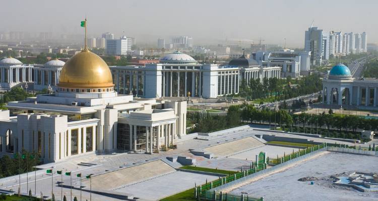 Moderne Stadtlandschaft aus weißen Marmor-Regierungsgebäuden mit einem goldkuppelförmigen Palast und breiten Alleen.