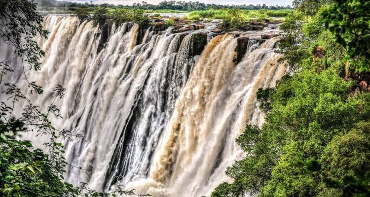 Mächtige kaskadierende Abschnitte der Victoriafälle, eingerahmt von lebhaftem grünem Wald.