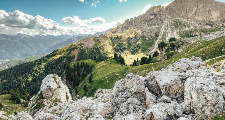 Rotsachtige bergkam met panoramische uitzichten over de vallei en gekartelde pieken onder verspreide wolken.