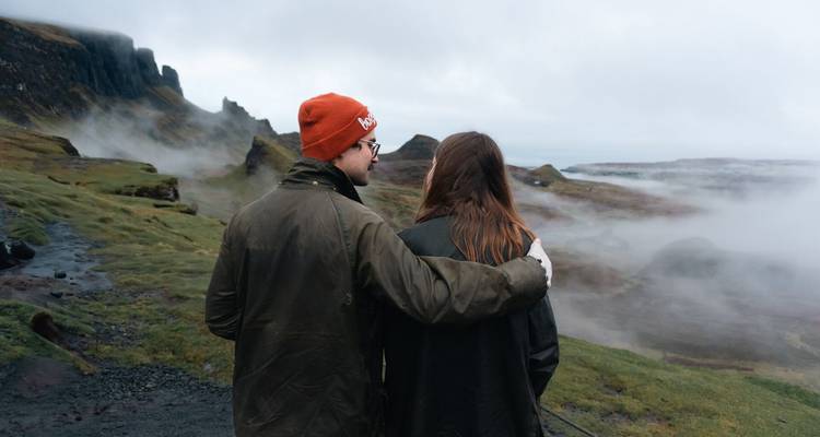 Homme avec le bras autour de son partenaire regardant au loin les Highlands écossaises brumeuses