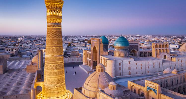 Le minaret Kalon et les madrasas historiques de Boukhara rayonnent dans les teintes crépusculaires au-dessus du paysage urbain antique.