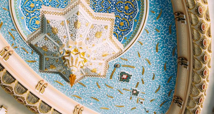 Détail orné géométrique bleu et doré du plafond d'un dôme islamique vu directement du dessous.