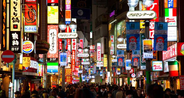 Neonverlichte straat in Tokyo vol met borden en menigten tijdens een levendige nachtscène.