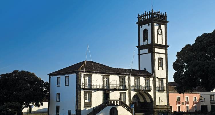 Histórico ayuntamiento de torre de reloj blanca con arcos de piedra y fondo de cielo azul