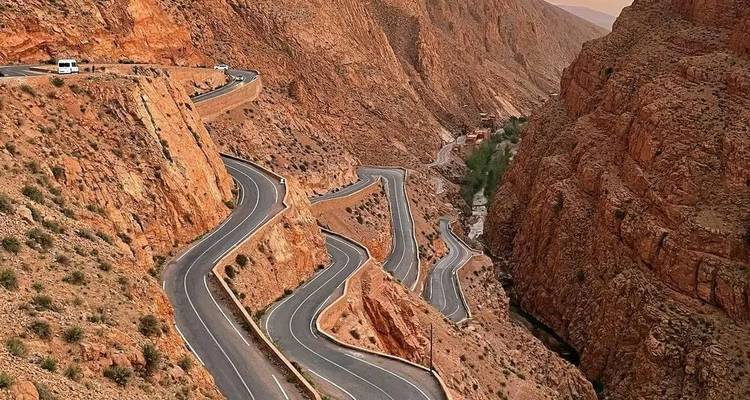 Route de montagne serpentine sculptant à travers les parois rouges abruptes des gorges du Dadès.