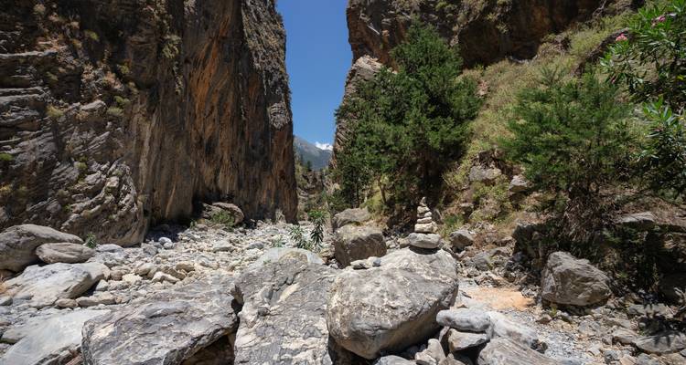 Narrow rocky gorge with boulder-strewn riverbed and towering cliffs in Samaria National Park.