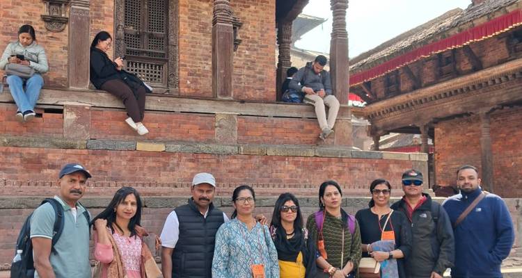 Similar small group image in front of Bhaktapur temple with seated locals nearby.