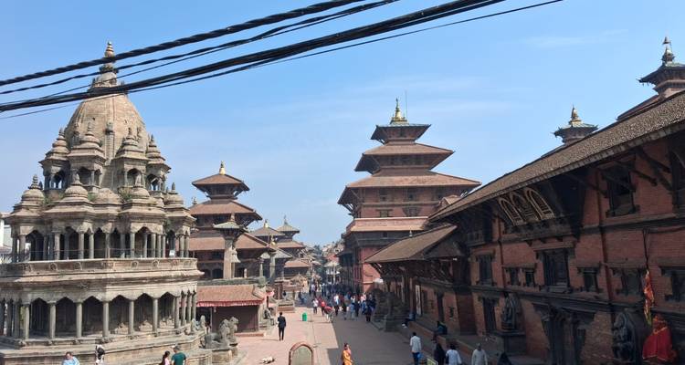 Historic street of Bhaktapur lined with temples and bustling visitors beneath overhead wires.