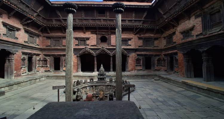 Stone courtyard with ornate central well and intricately carved pillars inside Patan palace.