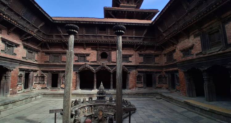 Alternate angle of Patan palace courtyard showing carved stone columns and tiered roofs.