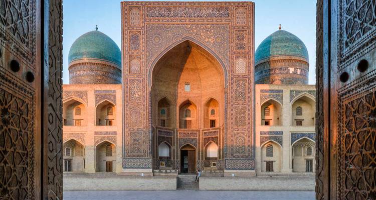 Magnifique portail de madrasa carrelé encadré par des portes en bois sculpté avec une douce lumière du soir.