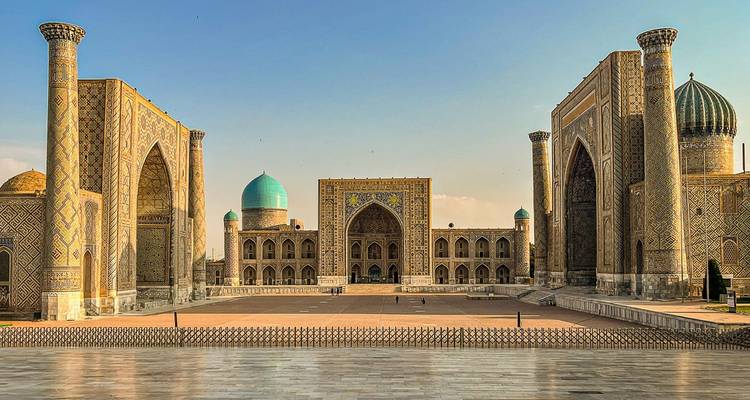 Vue panoramique des madrasas aux carreaux ornementés encadrant la place du Registan sous un ciel bleu dégagé