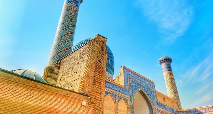 Plan en contre-plongée d'un minaret et de dômes carrelés de turquoise contre un ciel bleu éclatant