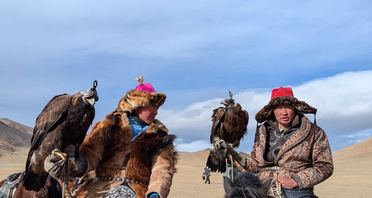 Deux chasseurs d'aigles kazakhs en vêtements traditionnels en fourrure tenant leurs aigles à cheval.