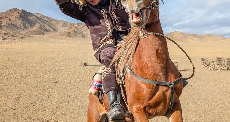 Cavalier en tenue traditionnelle faisant cabrer son cheval de manière spectaculaire dans la steppe ouverte.