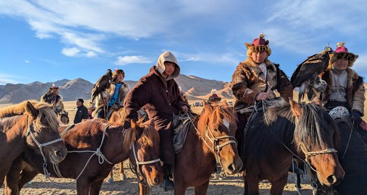 Rangée de chasseurs d'aigles à cheval en tenue traditionnelle alignés sur leurs chevaux.