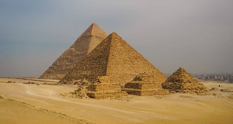 Deux grandes pyramides s'élevant des sables du désert de Gizeh sous un ciel brumeux