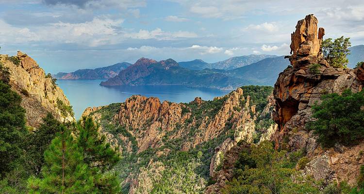 Felsige rote Granitformationen mit Blick auf einen ruhigen Mittelmeer-Golf und ferne Berge