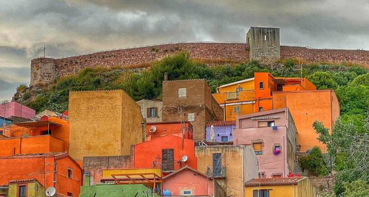 Ansammlung bunter Hanghäuser unter stimmungsvollem Himmel in der sardischen Stadt Bosa
