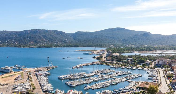 Luftaufnahme eines belebten Yachthafens voller Yachten vor bewaldeten Hügeln und blauer Lagune