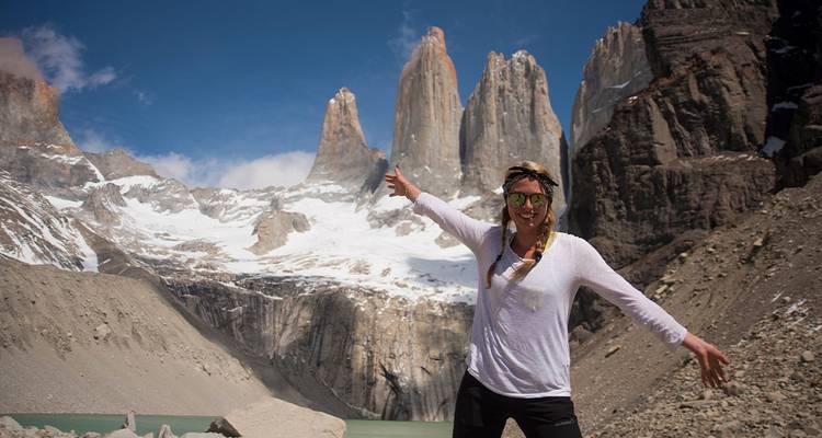 Randonneur souriant écartant les bras devant les imposantes aiguilles de granit des Torres del Paine