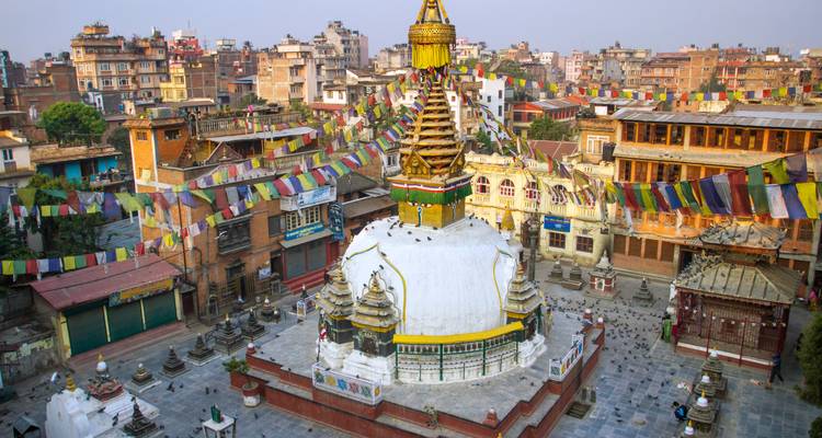 Weiße Stupa umgeben von bunten Gebetsfahnen beherrscht ein lebhaftes Kathmandu-Viertel.