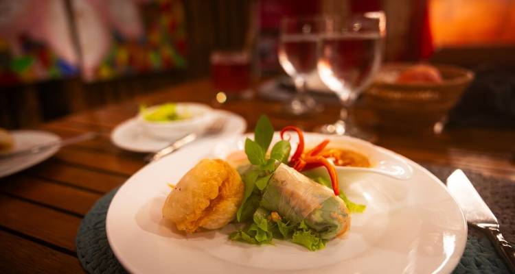 Fine-dining presentation of Cambodian appetisers on a white plate in a warmly lit restaurant.