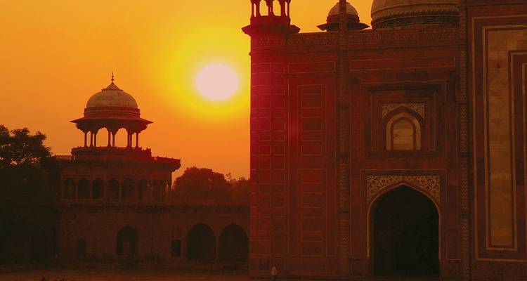 Silueta de arquitectura mogol con un sol naranja brillante poniéndose detrás.